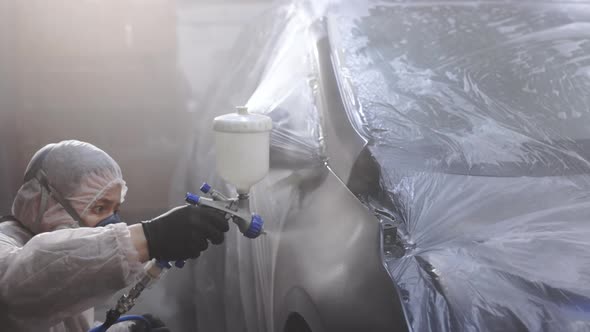 Painter Spraying Paint on Car Door in Special Booth