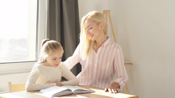Young Parent Mum Helping Cute Caucasian School Child Girl Doing Homework