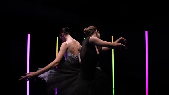 Camera Circular Motion Around Young Ballerinas Dancing on a Black Studio Background with Bright Neon alt
