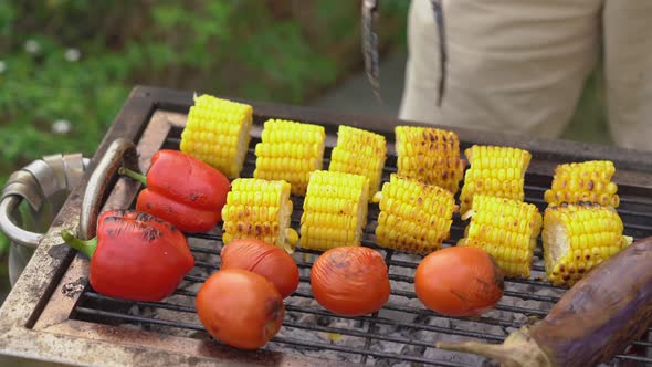A Young Man Cooks Vegetables and Shrimps on a Barbeque in His Backyard