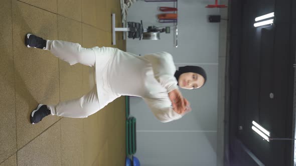 Arab Woman in a White Hijab Works Out in the Gym a Muslim Woman Squats in the Indoor Gym