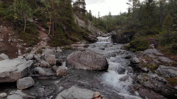 A Close Up of a Man Resting in the Middle of Raging Stream in a Mountain Valley alt
