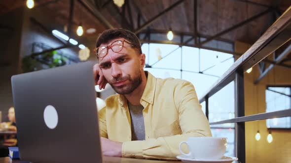 Millennial Male Hold Head with Hand Sitting at Table Falling Asleep Tired Man Fall Asleep Working at alt
