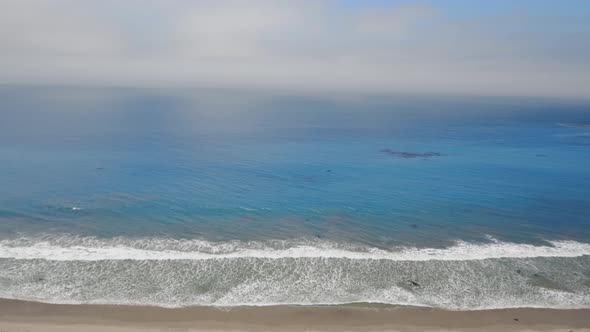 Aerial shot of foggy horizon, blue ocean and houses on the beach in Malibu, California, USA alt