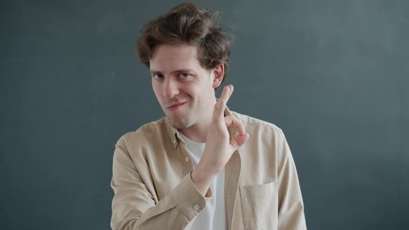 Slow Motion Portrait of Cheerful Guy Showing Ok Hand Gesture and Smiling Looking at Camera alt