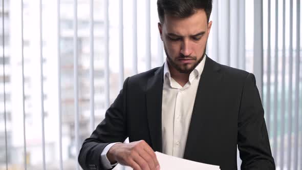 The camera zooms in on the face of a young manager, who is examining papers alt