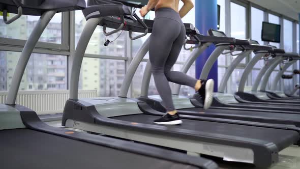 Young sporty Woman On Running Machine In Gym alt