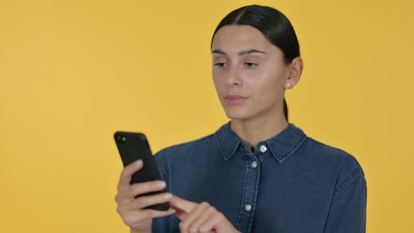 Latin Woman Using Smartphone, Yellow Background  alt