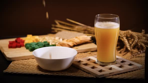 Salted Peanuts Fall Into Bowl Near Glass of Beer alt