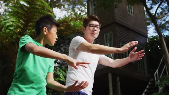 Happy asian fother exercising in garden with sonr, practicing tai chi together alt