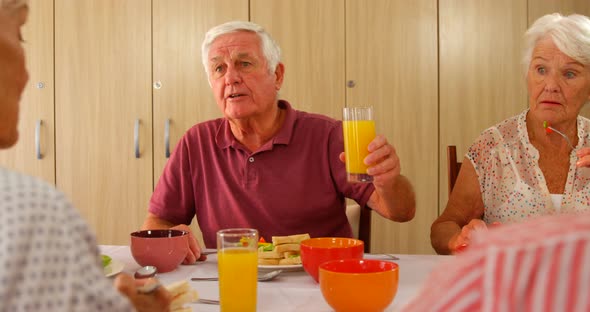 Senior man toasting his glass while having meal with friends alt