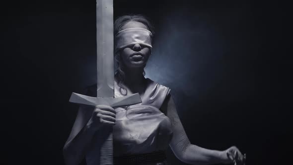 Greek Goddess Themis Stands on Black Background with Moving Smoke in White Clothes alt