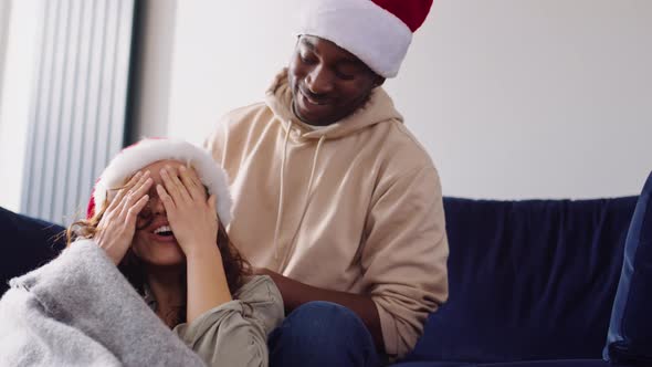 Man Pulling Santa Hat Over Womans Face As Couple Prepare For Christmas At Home