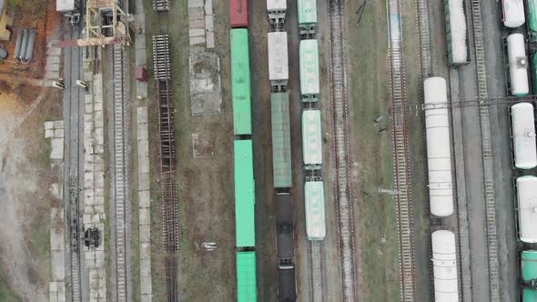 Flying above loaded cargo train wagons leaving industrial railroad station with freight containers  alt