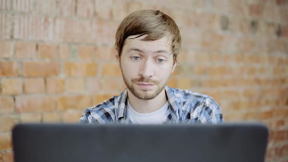 Sleepy tired young man sitting at office desktop with laptop, working and yawning in office alt