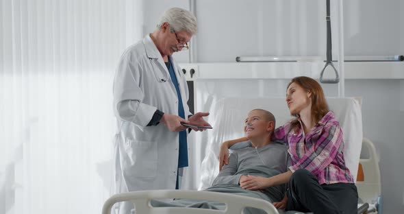 Aged Doctor Oncologist Discharging Teen Patient with Cancer alt