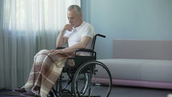 Lonely Old Man Sitting in Wheelchair at Hospital, Hopes to See Relatives alt