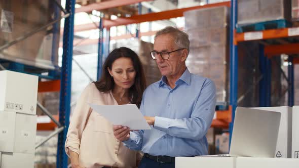 Mature woman and man working togetherness in the warehouse. Shot with RED helium camera in 8K. alt