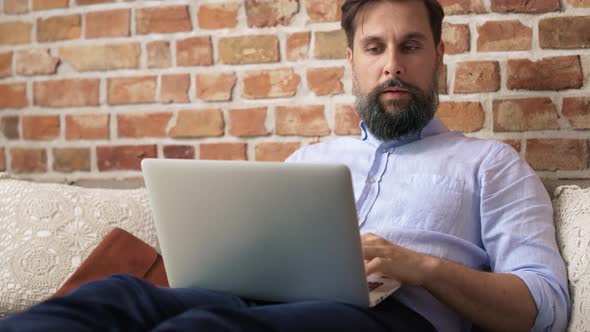 Video of man in a shirt sitting and using laptop. Shot with RED helium camera in 8K. alt