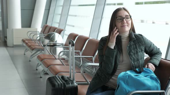Happy Woman Is Talking on Mobile Phone Waiting Her Flight in Airport. alt