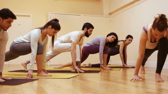 Trainer assisting group of people with stretching exercise alt