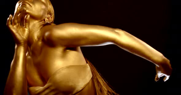 Half-naked Woman Is Covered By Golden and Glowing Paint Is Dancing Oriental Dance alt