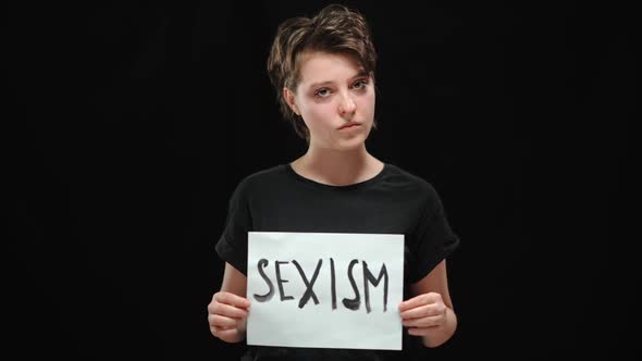 Portrait of Angry Young Brunette Woman Shaking Head No and Tearing Sexism Sign Looking at Camera alt