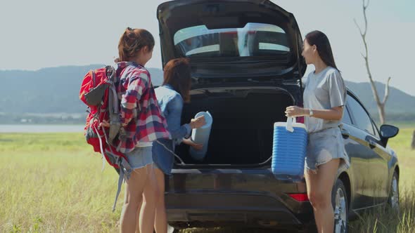 Group of a young teen Asian women helps to hold backpacks and ice coolers with friends camping.