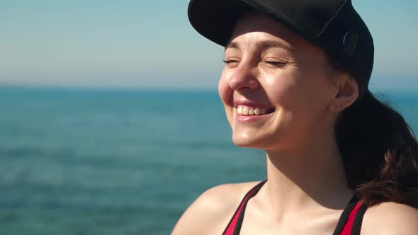 Closeup Portrait of Happy Young Woman in Black Cap Looking Away Closing Eyes Enjoying Sunny Day on alt