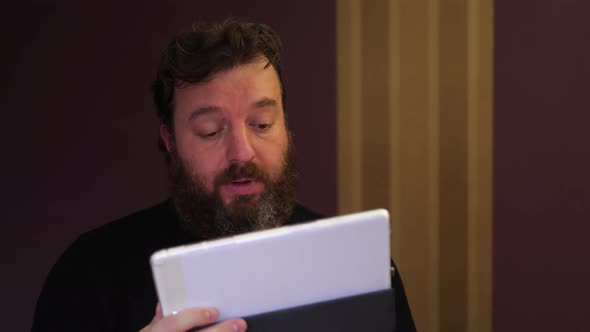 Portrait of bearded man while looking for something on the tablet