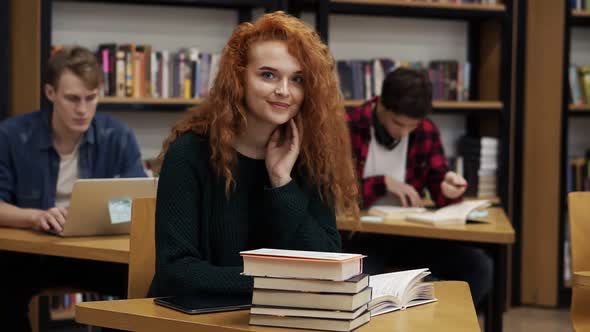Portrait of a Young Red Headed Curly Female Student Working on Her Thesis or Preparing for Exam alt