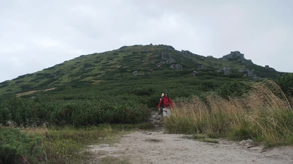 Tourist with a Backpack Goes Down Along the Stone Trail on Mountain Hill alt