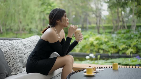 Cinematic Shot of Beautiful Young Asian Business Girl Wearing a Sexy Black Dress Holding a Cup of alt