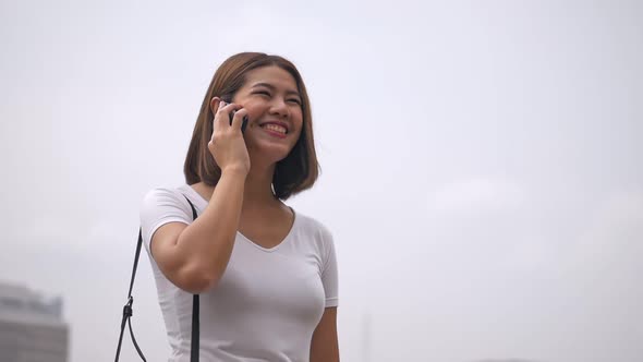 A beautiful Asian woman talks to cellphone beside the river.