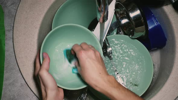 Woman washing dishes with a sponge alt