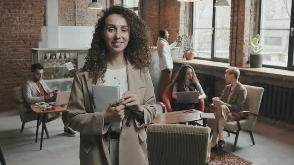 Young Businesswoman Posing for Camera with Notebook in Hands alt
