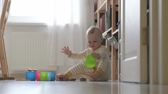 Little Baby Playing with Educational Colorful Toys at Home Sitting on Floor alt