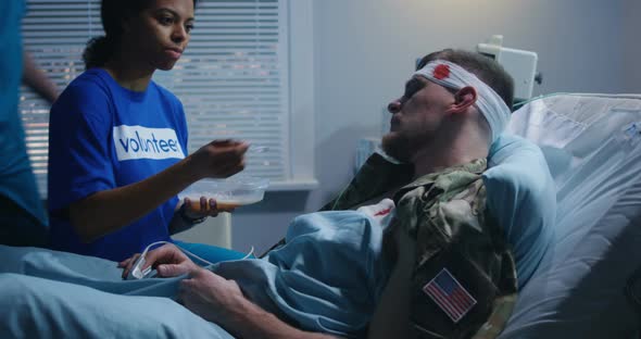 Nurse Feeding Injured Soldier in Hospital Bed alt
