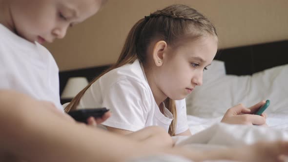 Cute Girl and Sweet Boy Playing in Video Game on Two Smartphones alt