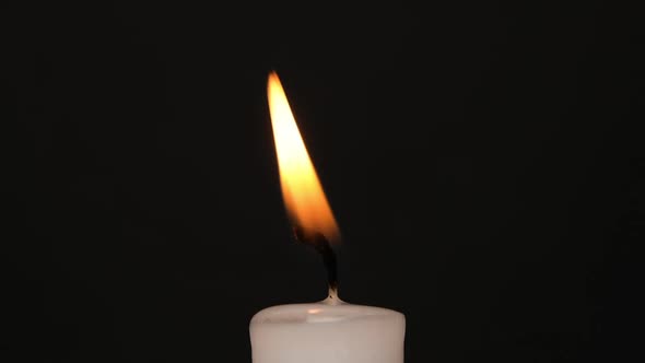 White Single Candle Flickering in the Dark