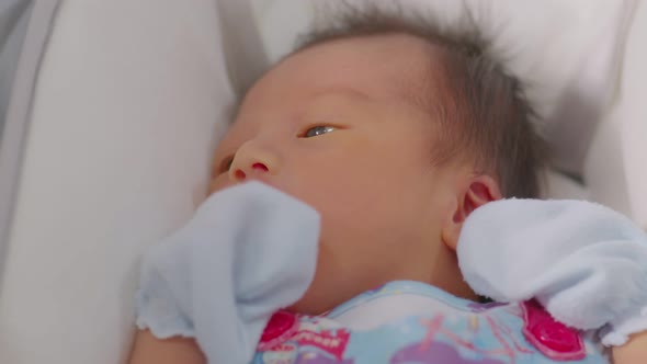 A happy newborn infant lying on a baby bed,smiling at the camera alt