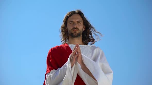 Jesus in Robe Praying Against Blue Sky Background, Asking God to Forgive Sinners alt