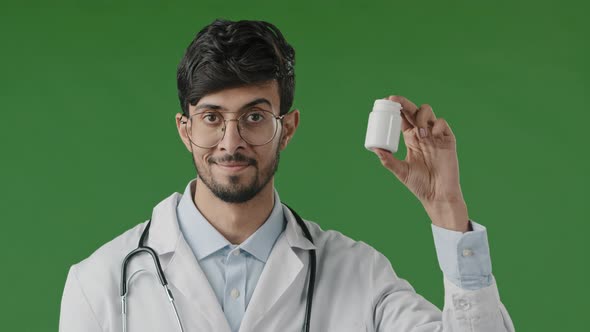 Indian Male Young Doctor Adviser in Medical Coat Standing Over Green Background Recommend at Camera alt