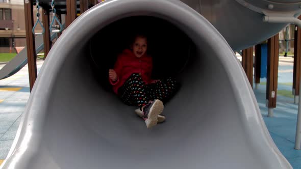 Amazed Young Lady Comes Down Grey Slide on Playground alt