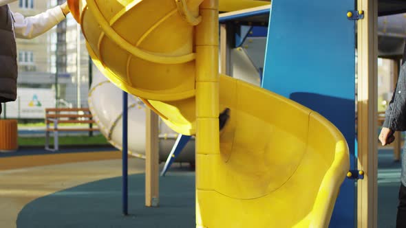 Happy Young Boy Coming down Spiral Slide in Urban Playground alt