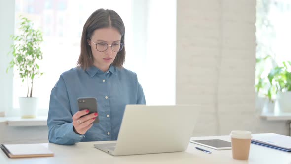 Young Woman Working on Laptop and using Smartphone at Work alt