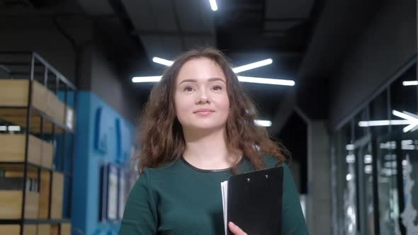 businesswoman walks along the corridor and holds folder with documents in hands alt