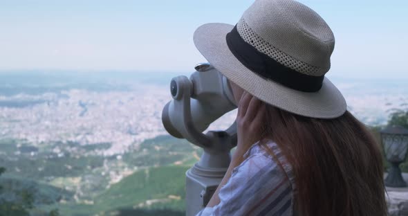 Young Woman in Hat Looks at the City Through a Telescope Explores Sights alt