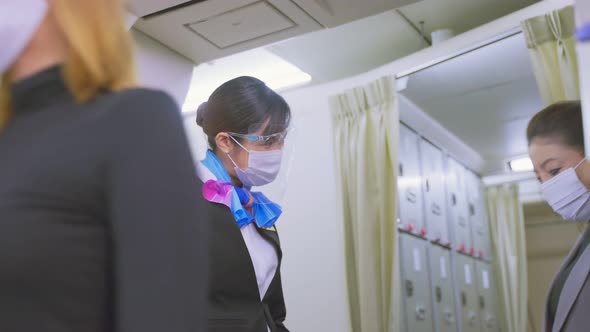 Flight attendants wearing face mask greeting passengers walking and ...