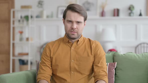 Portrait of Young Man Feeling Sad towards Camera at Home alt